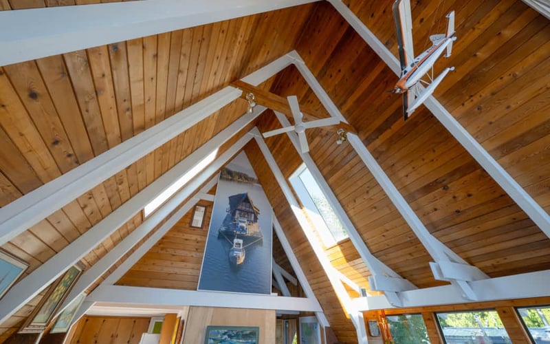 Vaulted wooden ceiling with white beams and nautical boat artwork on interior wall